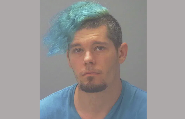 Individual with vibrant blue hair wearing a blue top, set against a neutral background.