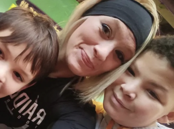 Close-up photo of a woman and two children, all smiling and leaning in closely, with a colorful background behind them.
