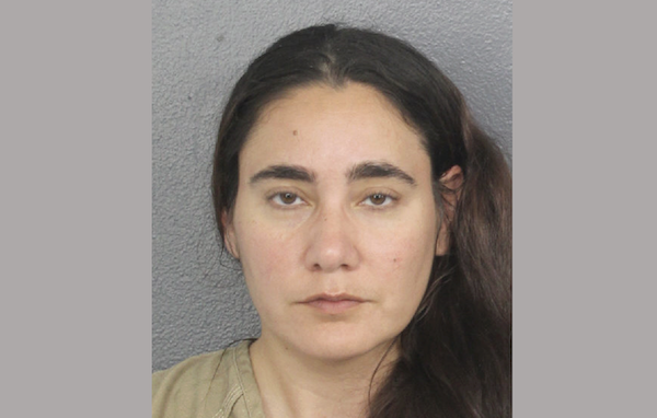 Close-up image of a woman with straight brown hair and wearing a beige shirt, photographed in front of a plain gray backdrop.