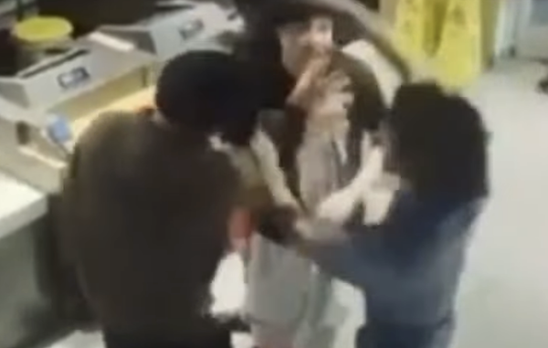 A view from above captures a confrontation as two men appear to argue while an employee attempts to separate them at a McDonald's.