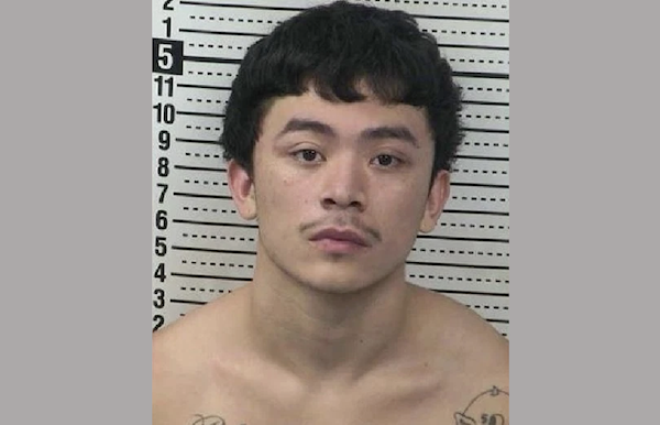 Police booking photo of a shirtless male in his early twenties, black hair, with tattoos on his shoulders, facing the camera with a neutral expression.