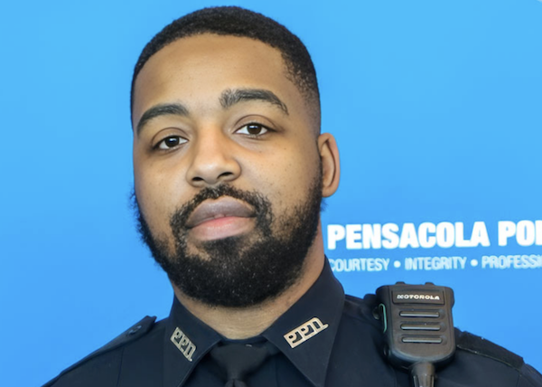 Head-and-shoulders photo of a bearded police officer in dark uniform with radio mic visible, posed in front of a blue Pensacola Police background.