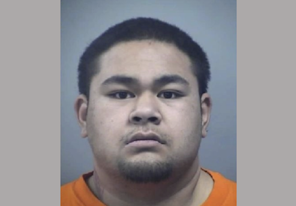 Head-and-shoulders portrait of a man with a neutral expression, closely cropped hair, and a trimmed goatee in an orange top.
