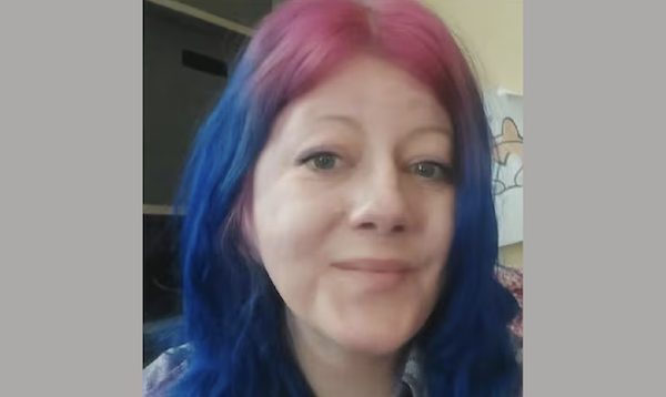 Woman with bright two-tone hair, pink on top and blue below, looks toward the camera.
