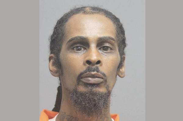 Close-up mugshot image showing a man in an orange jail uniform facing the camera.