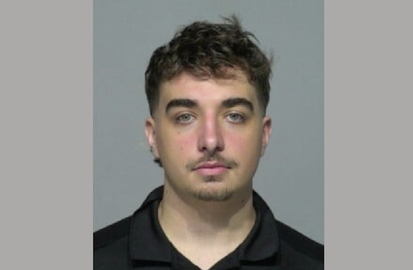 Mugshot-style portrait showing a young man looking directly at the camera with a neutral expression.
