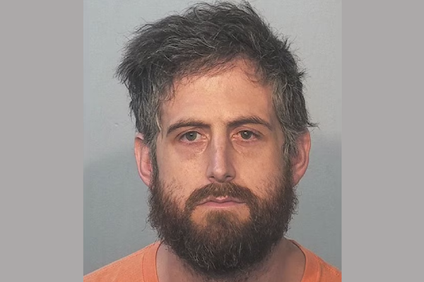 Front-facing mugshot of a bearded man with messy hair and a serious expression.